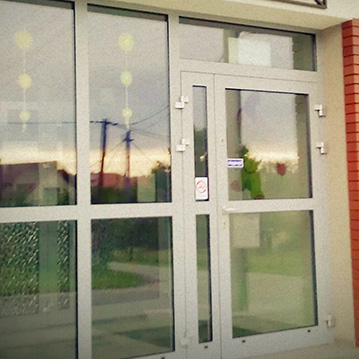 Glass door entrance to a building with glass windows next to the door.