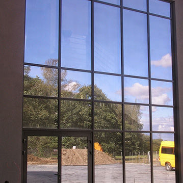 Large reflective glass wall featuring an entrance door in the lower left corner.