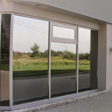 Glass window with three sections reflecting outdoor landscape in bright daylight.